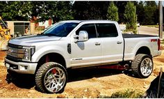 a white truck parked on top of a dirt covered field next to a construction site