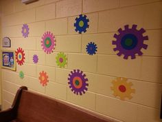 a wall with gears painted on it next to a bench in front of a door