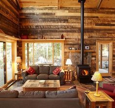 a living room filled with furniture and a fire place in the middle of a wooden wall