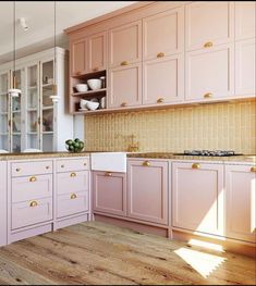 a kitchen with pink cabinets and wooden floors in the center is filled with white dishes