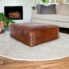 a brown leather ottoman sitting on top of a rug in front of a fire place