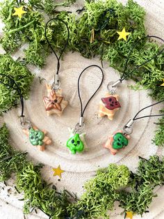 four charms with different designs on them are arranged in a circle surrounded by greenery