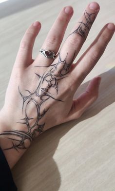 a person's hand with tattoos on it and a ring in front of them