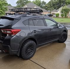 the rear end of a black toyota rav parked in front of a house on a rainy day