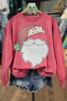 a red sweatshirt with a santa clause on it and ripped shorts in front of a store display