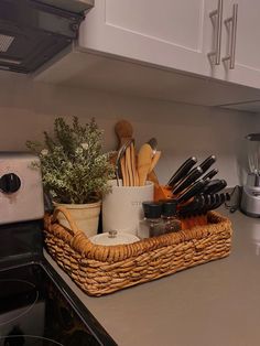 a kitchen counter with utensils in a basket on top of the stovetop