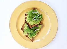 two pieces of bread with lettuce and onions on it sitting on a yellow plate