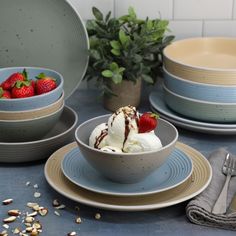 a bowl with ice cream and strawberries in it sitting on a blue table cloth