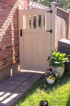 a white potted plant sitting in front of a wooden gate on the side of a brick building