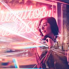 a woman standing in front of a neon sign