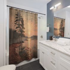 a bathroom with a shower curtain that has a lake scene on it and trees in the background