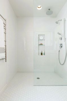 a white bathroom with a shower, toilet and shelf on the wall next to it