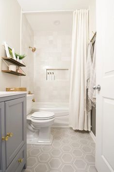 a white toilet sitting in a bathroom next to a sink and shower curtain on the wall