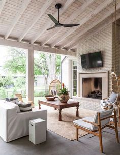 an outdoor living room with white furniture and a tv mounted on the wall above it