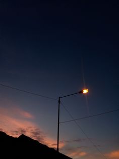 the sun is setting on top of a hill with power lines in front of it