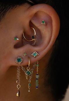 a person wearing ear piercings with different colored stones and chains on their ears,