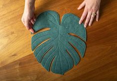 a person is making a monster leaf out of felt on the floor with their hands