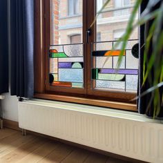 a window with stained glass on it and a plant in the corner next to it