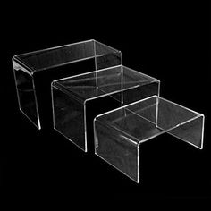 three clear acrylic tables on black background