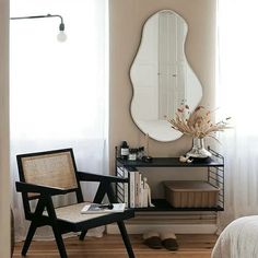 a bedroom with a chair, mirror and bookshelf