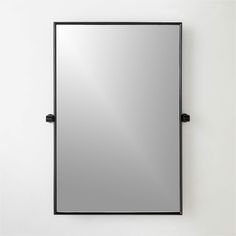 a mirror mounted to the side of a wall next to a white wall with black handles