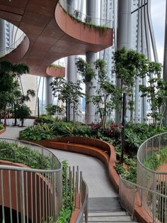 an indoor garden with trees and plants on the sides, surrounded by metal railings