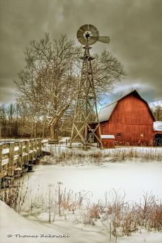 an old red barn and windmill in the snow