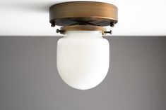 a light fixture with a white glass shade hanging from it's center point in a room