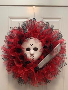 a red wreath with a mask and knife hanging from it's front door,