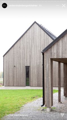 two wooden buildings sitting next to each other on top of a grass covered field and gravel road