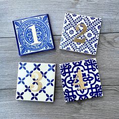 four blue and white tiles with the number one on them, all decorated in gold