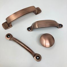 three different types of handles and pulls on a white surface, one is shiny bronze