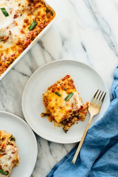 two plates with lasagna casserole on them and a blue towel next to it