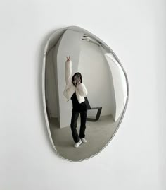 a woman standing in front of a mirror with her hand up to the side and arms raised