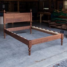 a wooden bed frame sitting on top of a cement floor