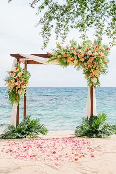 an outdoor wedding setup on the beach with flowers and greenery in the foreground