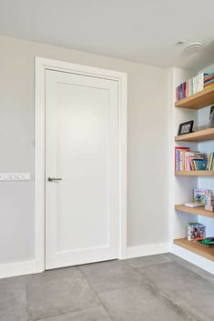 an empty room with bookshelves and a door in the center, on concrete flooring