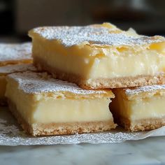 four pieces of dessert sitting on top of a white paper covered tablecloth with powdered sugar