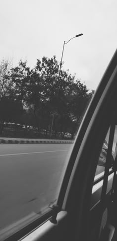 black and white photograph of the back window of a car with trees in the background