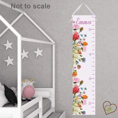 a child's growth chart with flowers and stars on the wall next to a bed