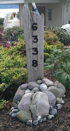 a wooden sign with the word peace written on it in front of some rocks and bushes