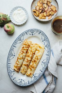 some food that is on a plate next to bowls and spoons with fruit in them