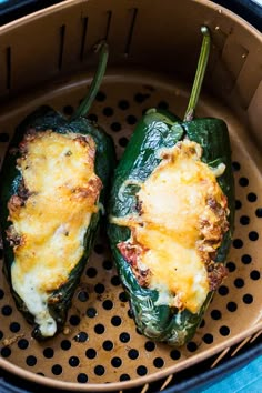 two stuffed peppers sitting in an air fryer with cheese on the top and bottom