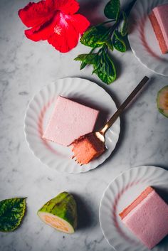 two plates with slices of cake on them next to a flower and some green leaves