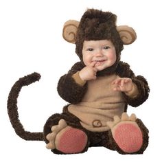 a baby in a monkey costume sitting on the ground with his hand up to his mouth