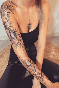 a woman is sitting on the floor with her arm tattoos tattooed to look like flowers