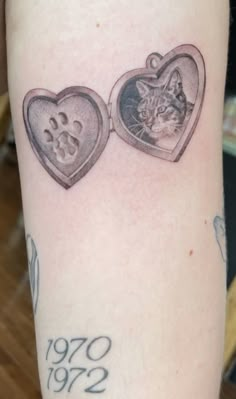 a tattoo with two hearts and a cat on it's arm, one has a paw inside the heart