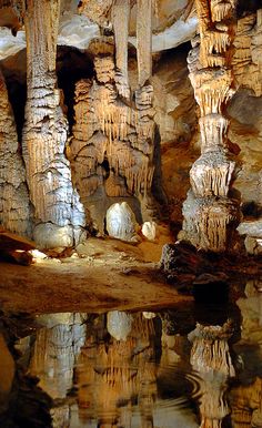 the inside of a cave with many columns and carvings on it's walls, reflecting in water