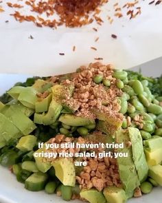 a white plate topped with lots of green vegetables next to a pile of brown rice