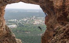 a man hanging from a rope on top of a cliff